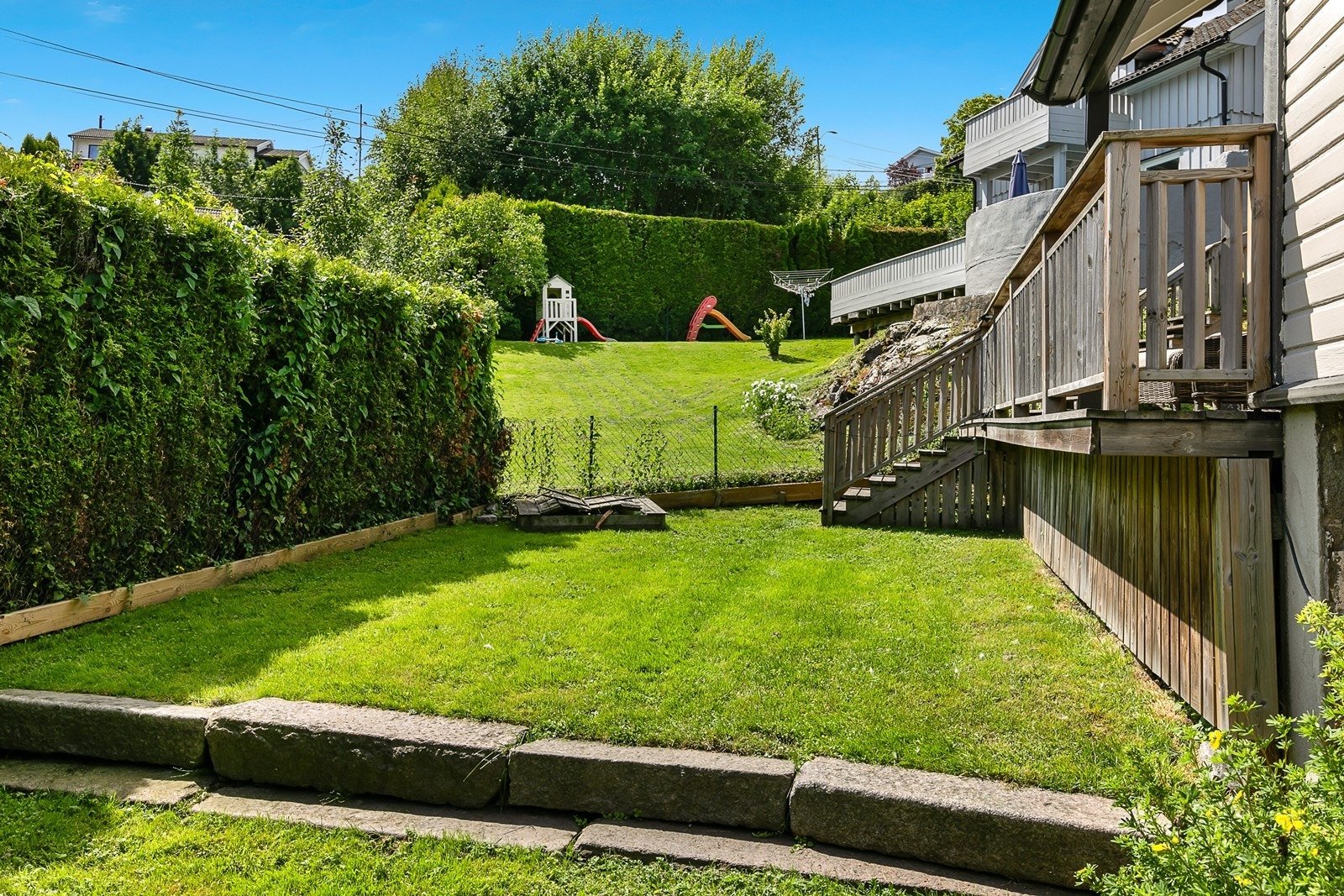 Fra verandaen er det trapp ned til hagen med gressplen og hekk. Galleribilde