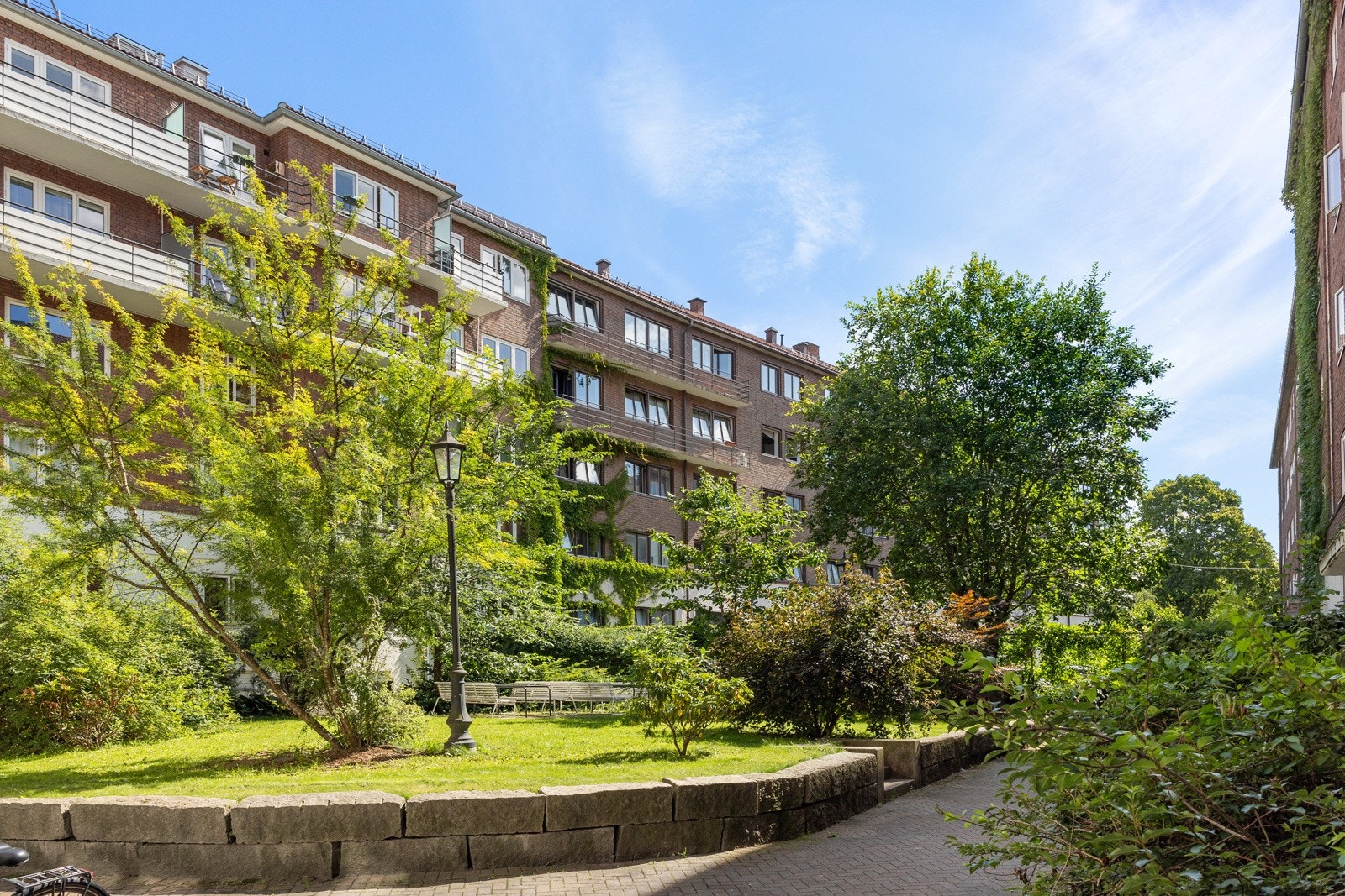 Grønn, frodig lunge med sittegruppe mellom byggene. Galleribilde