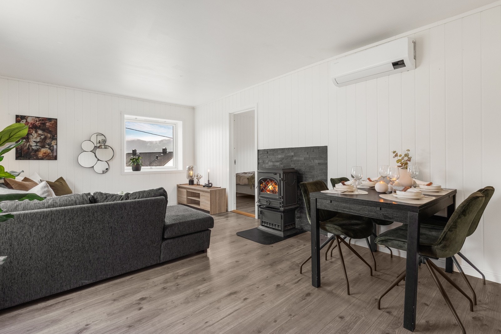 Koselig stue med varme detaljer og god belysning. Legg merke til at leiligheten varmes opp av både vedfyring, men også varmepumpe. Galleribilde