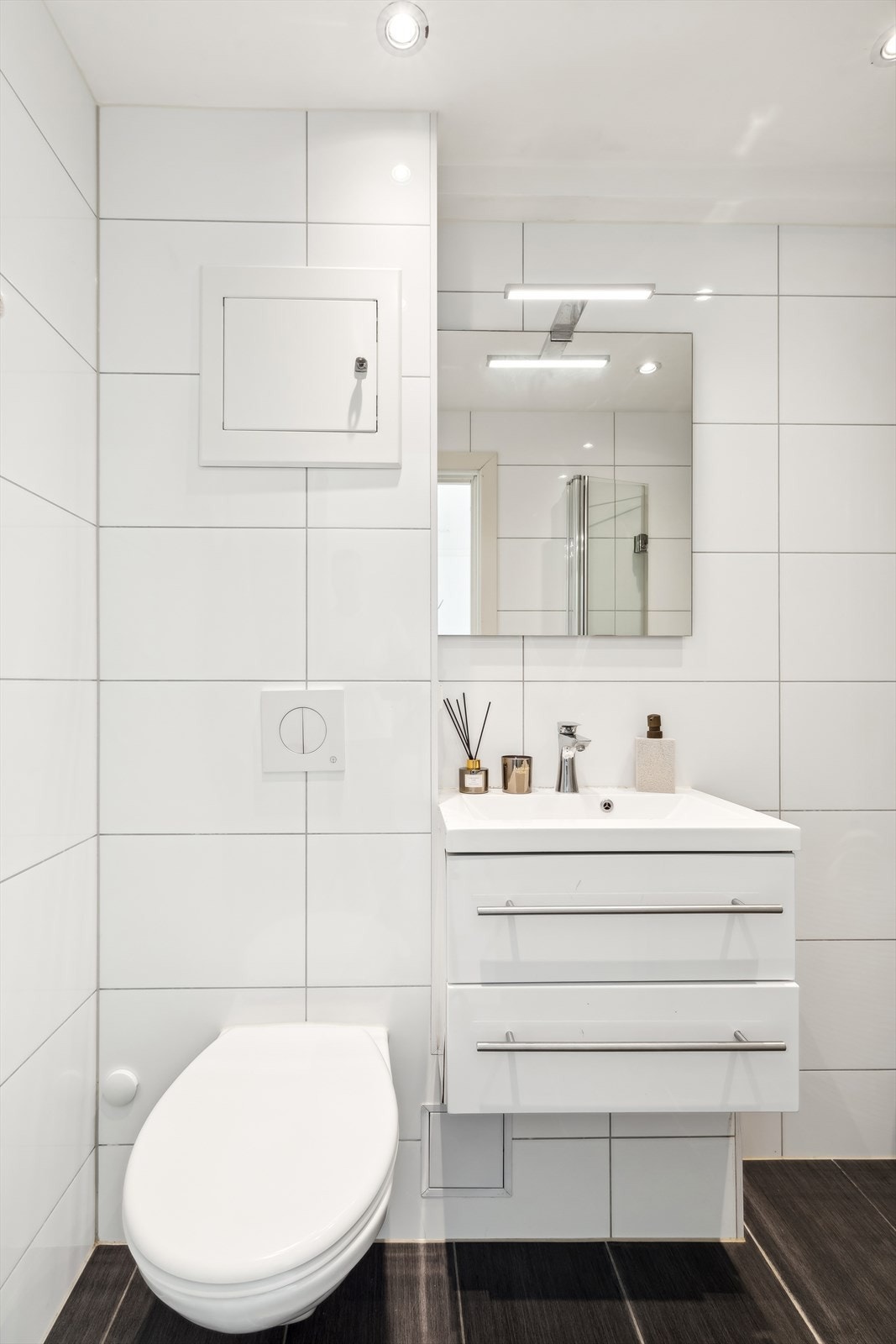 Badet består av vegghengt toalett, servant med underskap, speil med overlys, inn-/utadslående dusjdører og opplegg for vaskemaskin. Galleribilde
