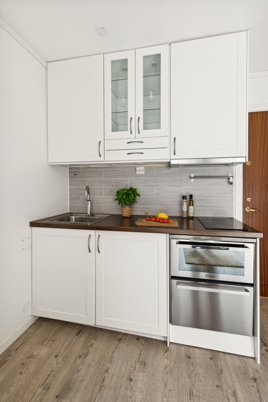 Kjøkkenet består av innredning med lakkerte 1-speils profilerte fronter, 2 stk. glassfronter i overskap, laminat benkeplate med fliser over, enkel oppvaskkum, kjøkkenventilator i stål antatt med kullfilter Galleribilde
