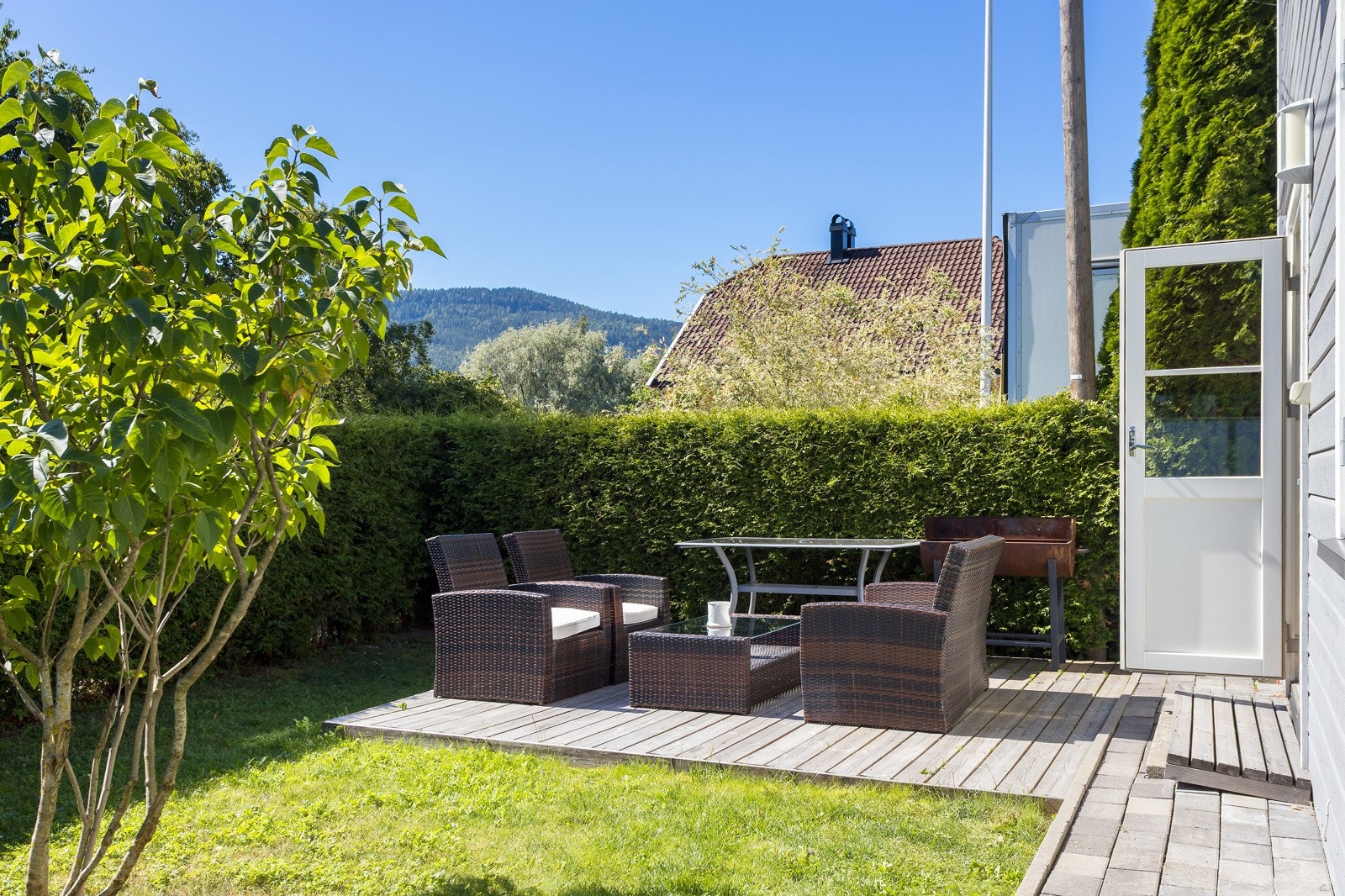 Terrasse og hage utenfor hyggelig liten eldre enebolig Galleribilde