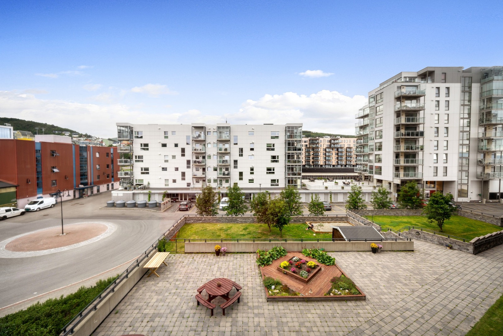 Meget pent opparbeidet fellesområde med gressplen, blomsterbed, sandkasse for de minste, og sitteplasser Galleribilde