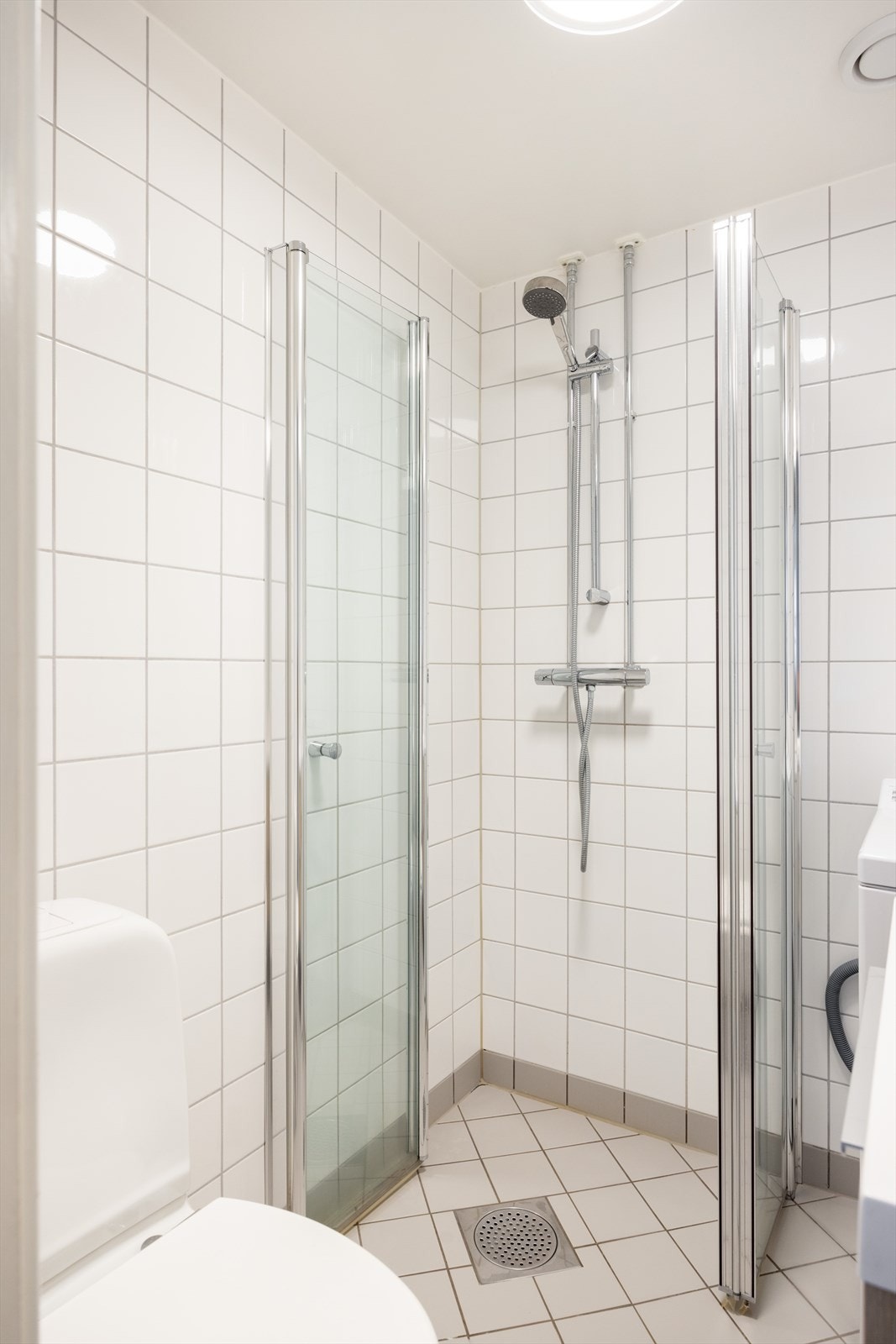 Badet er innredet med klosett, servant nedfelt i innredning, speil og dusjhjørne med svingbare glassdører. Galleribilde