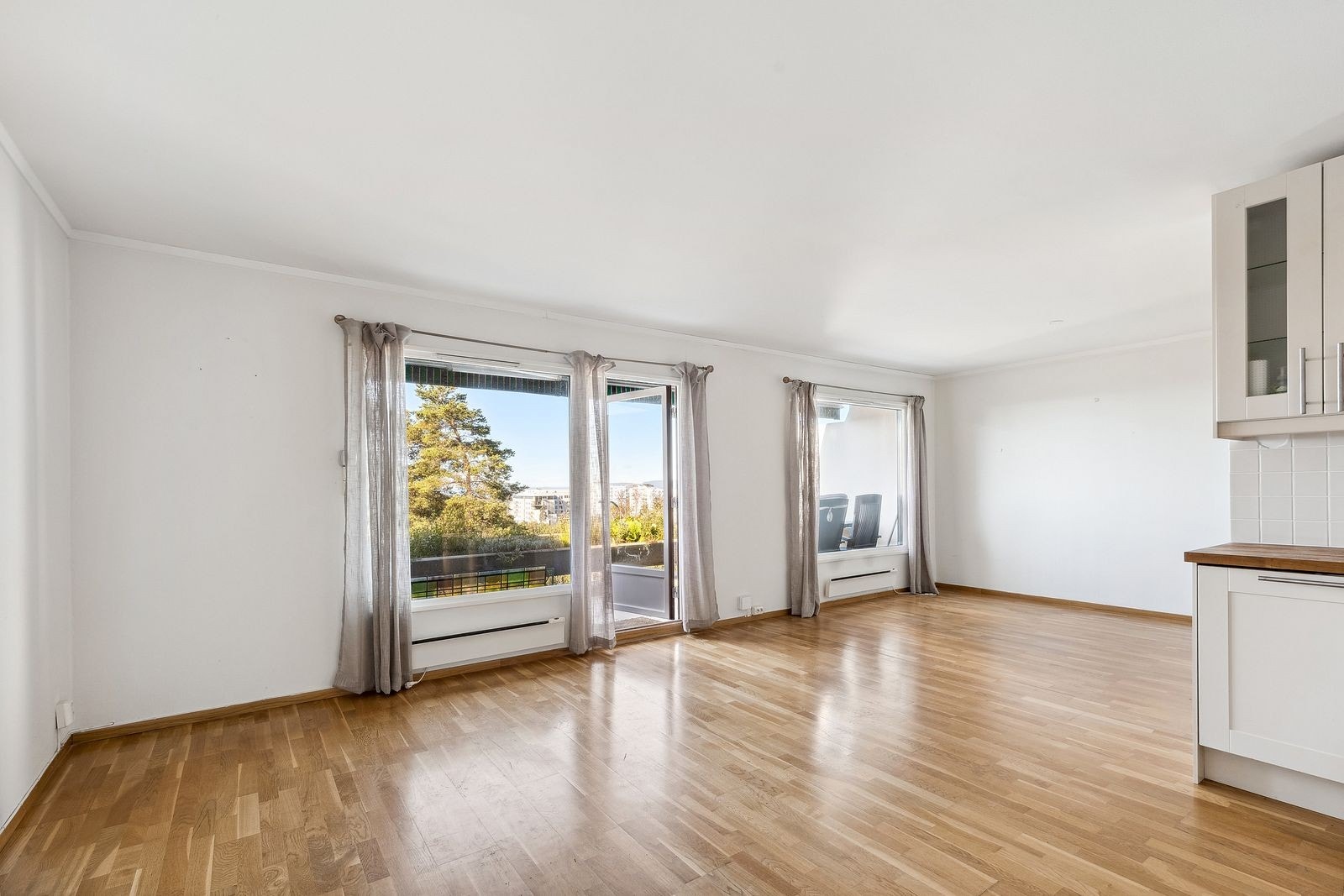 Åpen kjøkken/stue løsning med store vindusflater og utgang til balkong Galleribilde