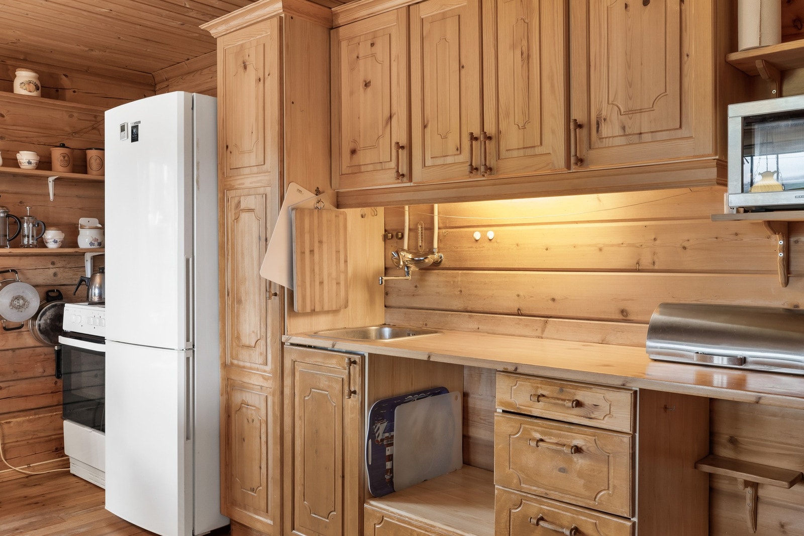 Kjøkken som del av stuen med innredning med
profilerte fronter av furu og benkeplate av heltre
med nedfelt servant. Galleribilde