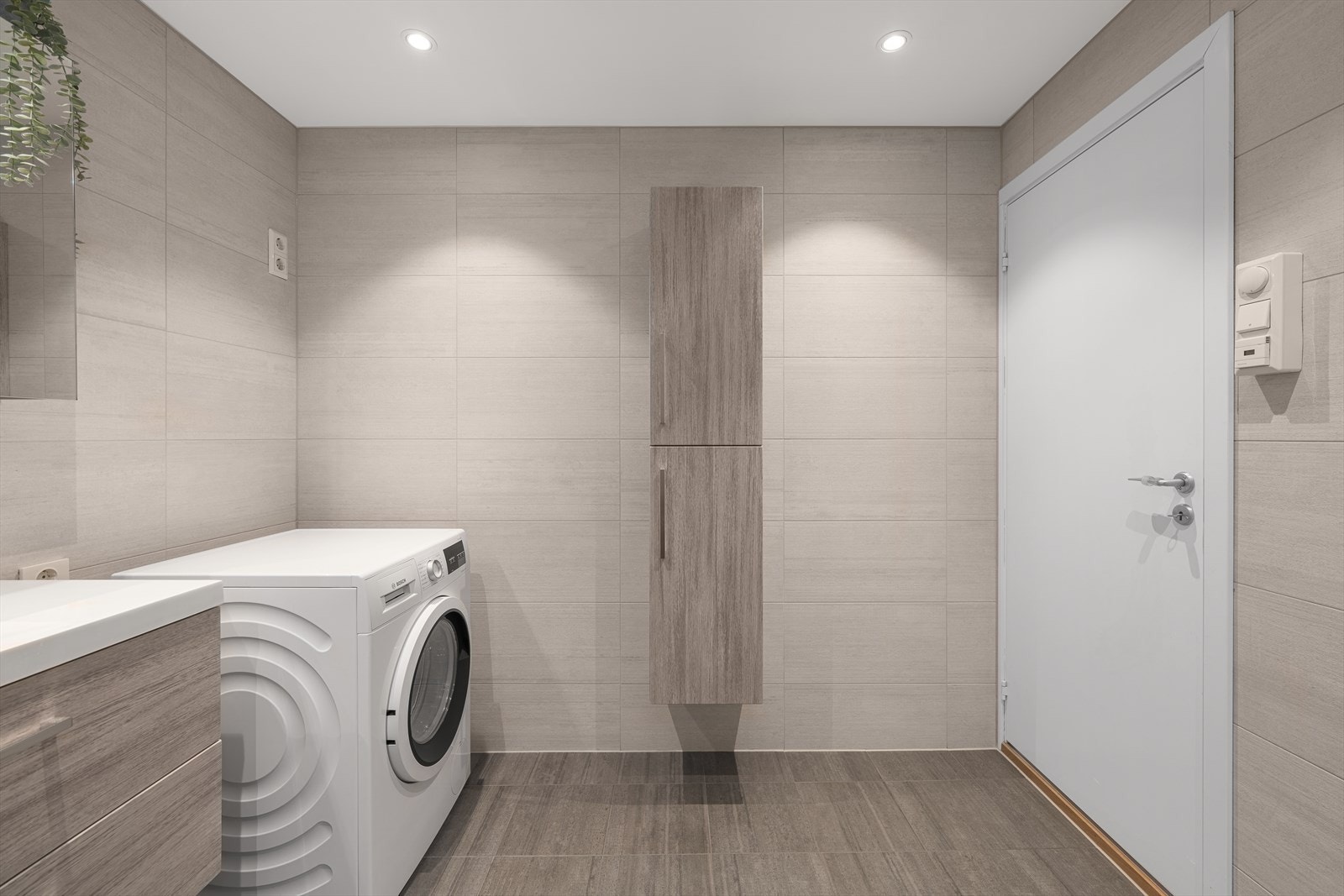 Det er store beige fliser på vegg, og mørkere fliser på gulv. I tillegg er badet utstyrt med elektrisk gulvvarme. Galleribilde