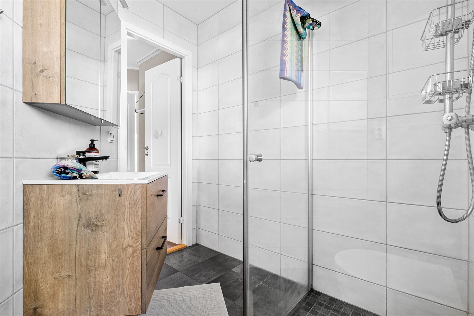 Badet er innredet med nedfelt servant, veggmontert toalett, dusjvegger/hjørne og opplegg for vaskemaskin. Galleribilde