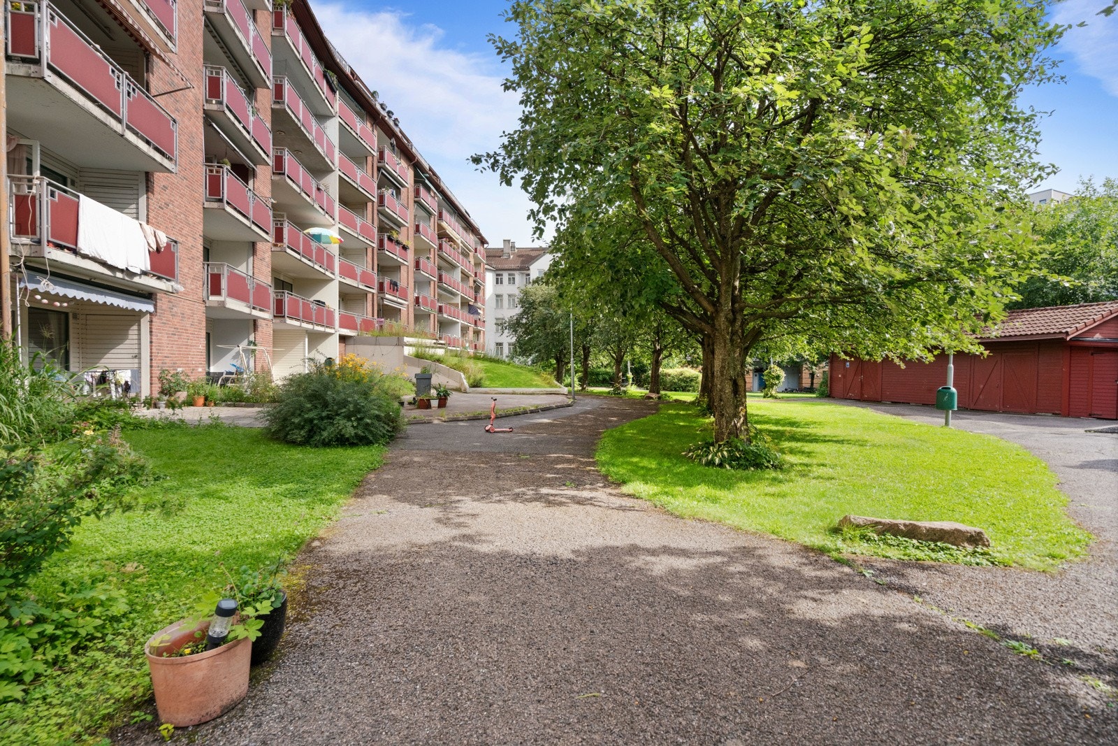 Felles eiet tomt. Bakgård opparbeidet med asfalterte gangveier, plenarealer, lekeapparater, sittebenker, sykkelbod, busker trær og annen beplantning. Galleribilde