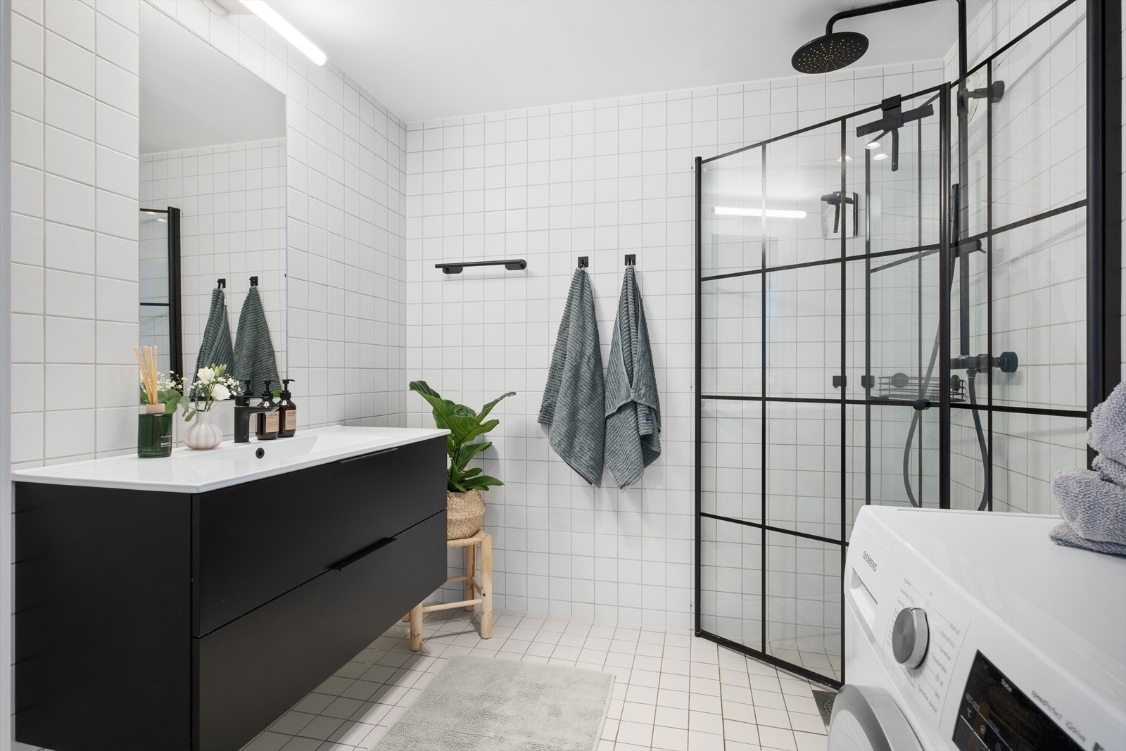 Flislagt bad med servantinnredning med underskap, veggmontert speil, dusj med "rainfall" dusjgarnityr, innfellbare dusjvegger og veggmontert wc. Opplegg for vaskemaskin og tørketrommel. Galleribilde