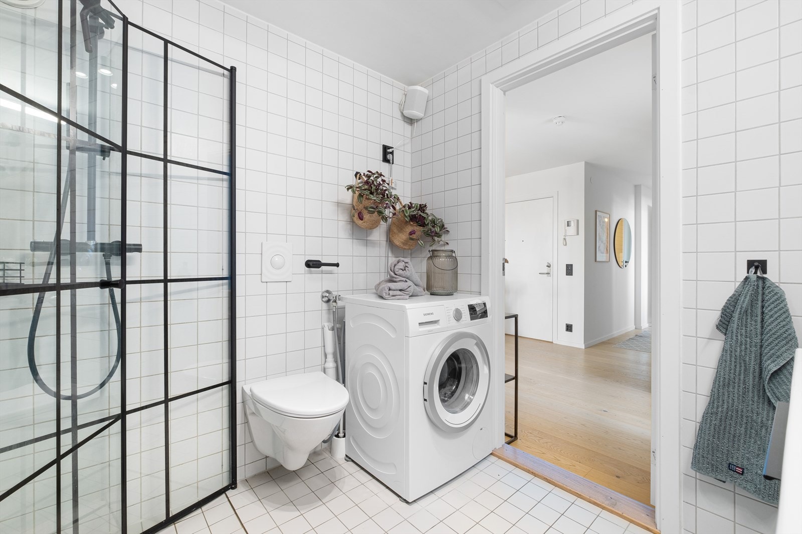 Flislagt bad med servantinnredning med underskap, veggmontert speil, dusj med "rainfall" dusjgarnityr, innfellbare dusjvegger og veggmontert wc. Opplegg for vaskemaskin og tørketrommel. Galleribilde