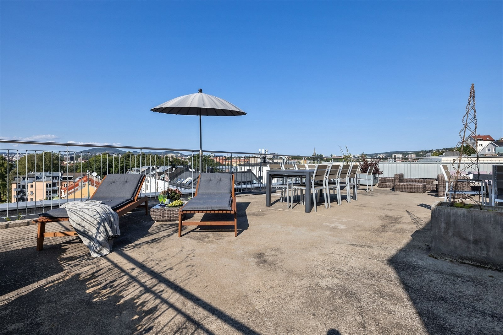 Takterrassen er utstyrt med felles møbler som solsenger, større spisebord og en koselig sittegruppe med tilhørende puter Galleribilde