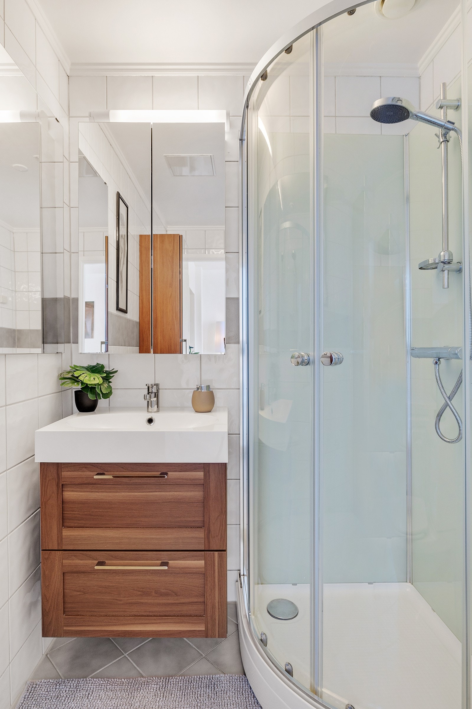 Badet inneholder vegghengt servantinnredning med skuffer og heldekkende servant, speilskap med overbelysning, gulvstående wc og dusjkabinett. Galleribilde