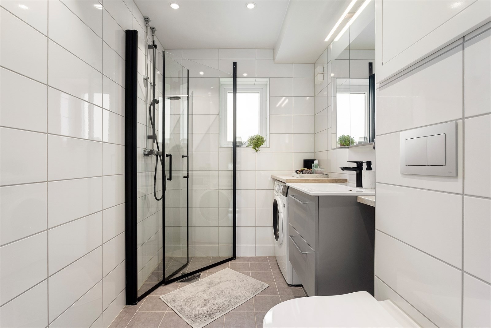Lekkert og moderne flislagt bad med gulvarme og downlights taket. Badet ble pusset opp i regi av borettslaget i 2021. Galleribilde