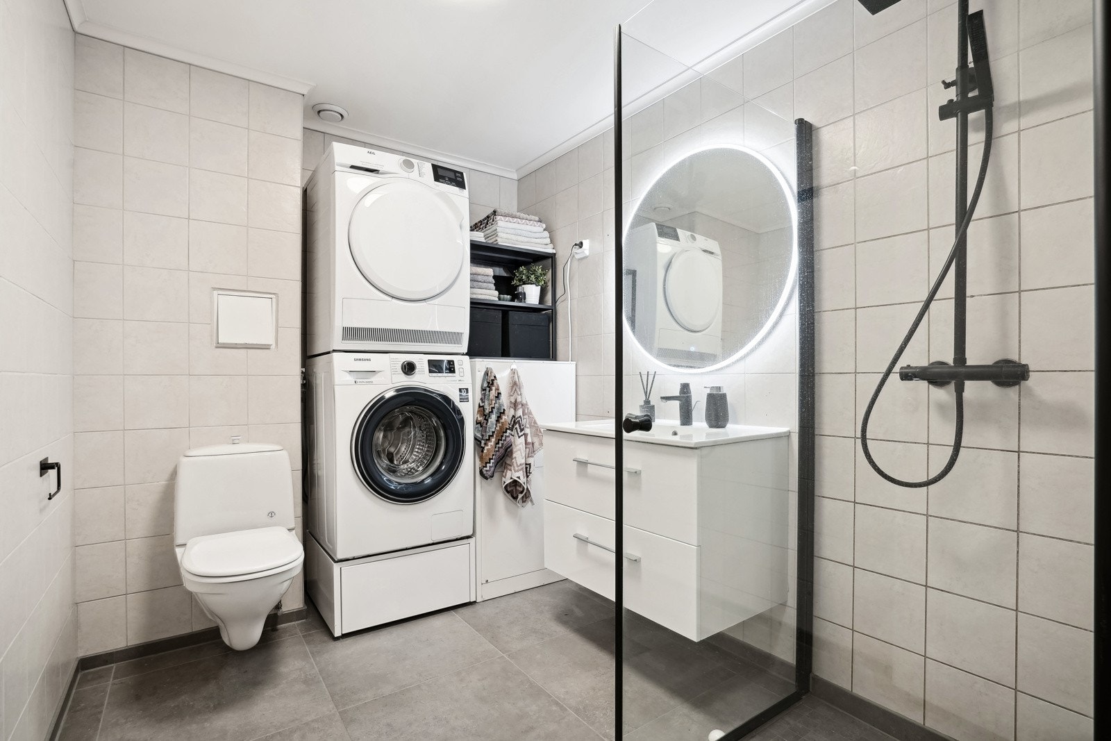 Flott flislagt bad med gulvvarme, opplegg for vaskemaskin, vegghengt toalett, servant og baderomsinnredning. Galleribilde