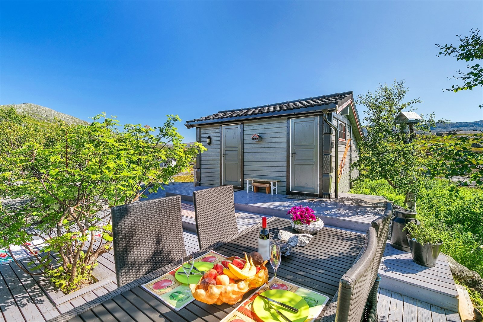 Pent opparbeidet eiendom med terrasseareal omkranset av prydbusker og beplantninger. Galleribilde