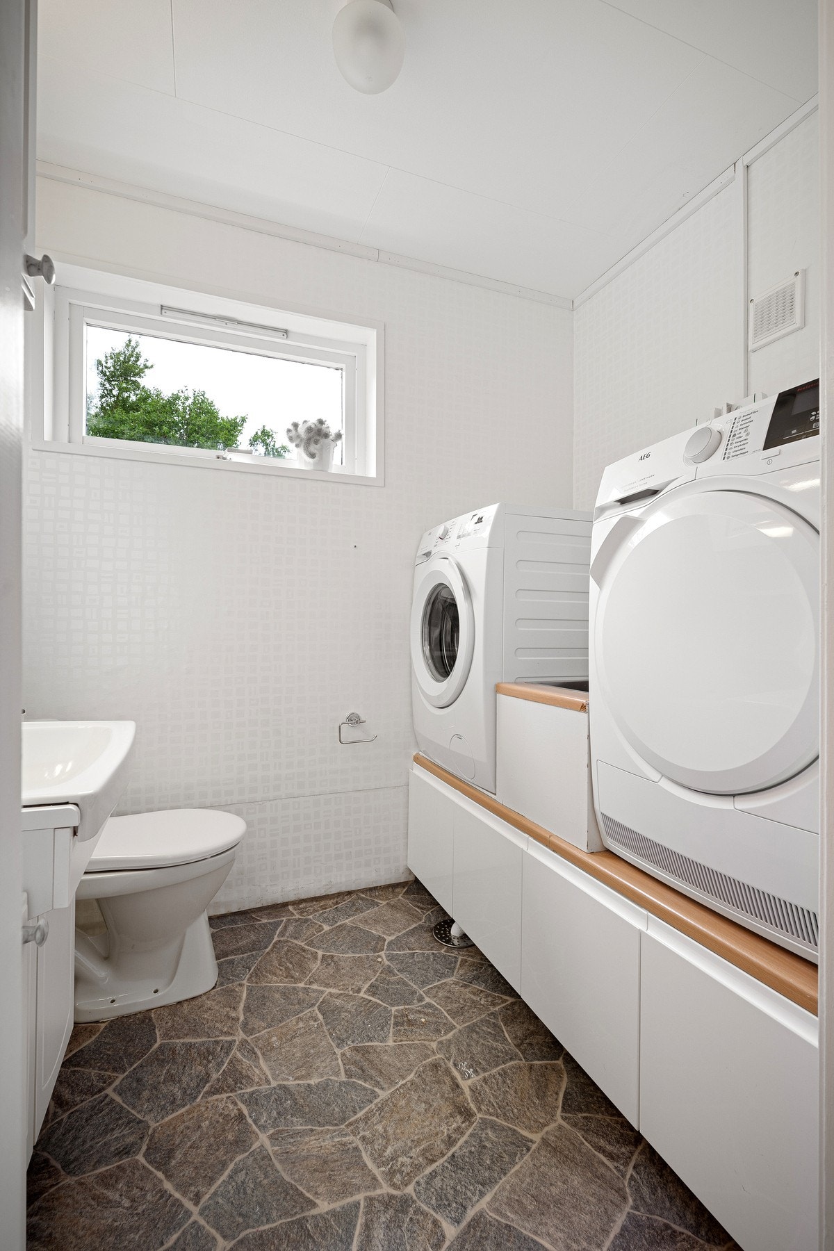 Rommet har opplegg og god plass til vaskemaskin, og det er etablert skyllekar med benkeplate mellom vaskemaskin og tørketrommel Galleribilde