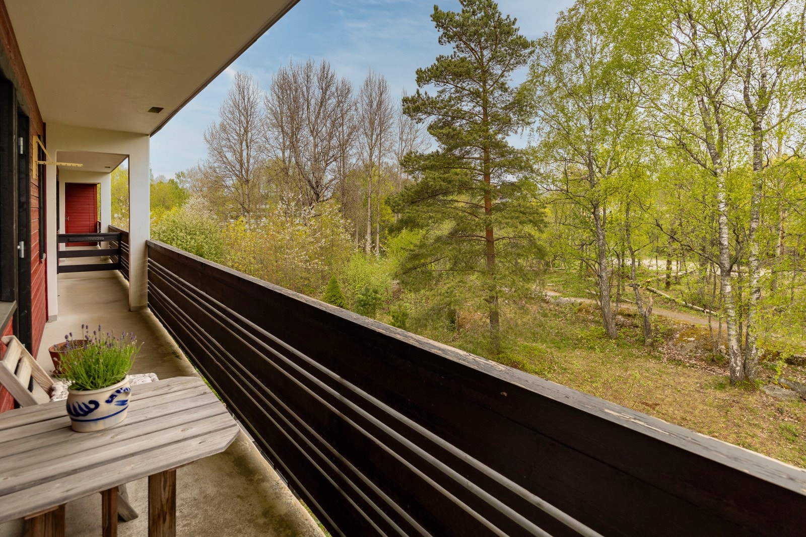 Balkongen har gulvflate av betong. Rekkverk av tre. Galleribilde