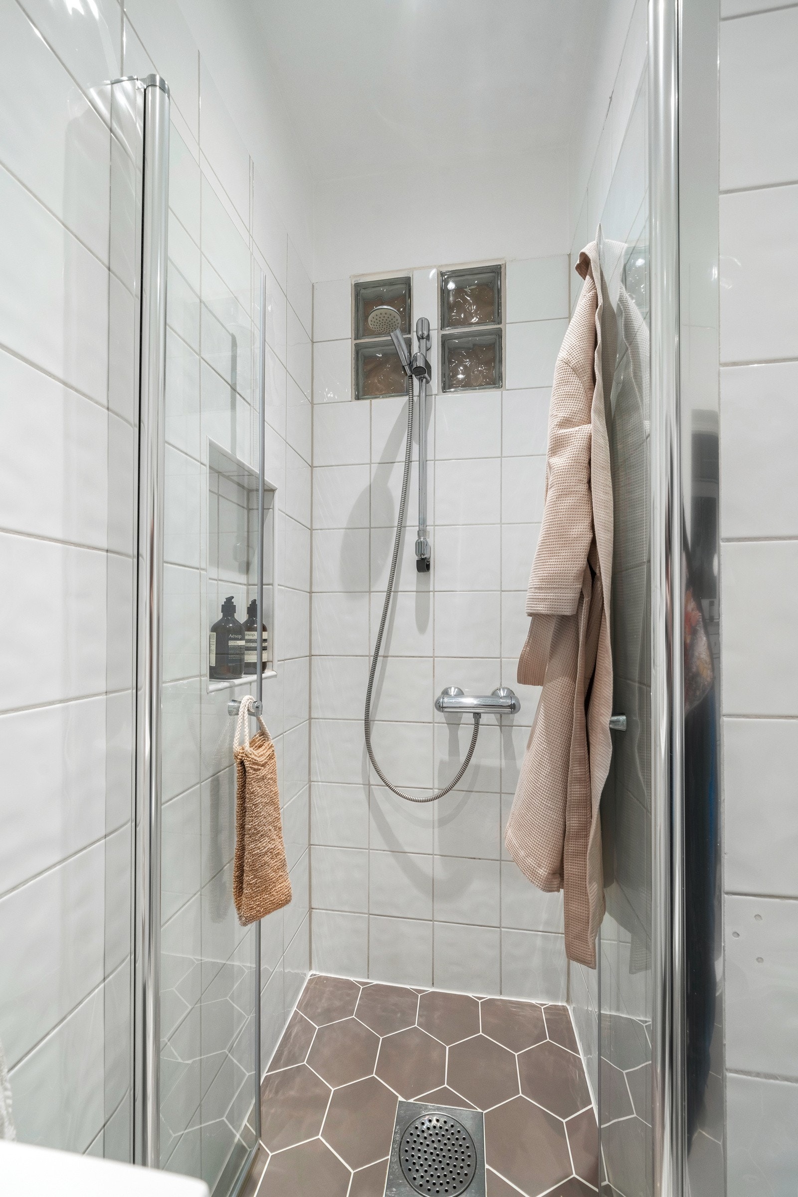 Badet kombinerer stil og funksjonalitet med et smart dusjhjørne som utnytter plassen optimalt, noe som gir en praktisk løsning. Dusjdørene er nye fra 2018. Galleribilde