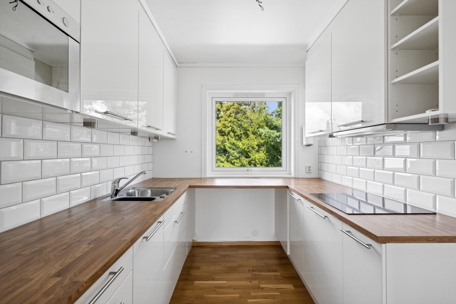 Boligen har et pent kjøkken med hvit innredning med slette dører og benkeplate i laminat. Det er montert fliser mellom benke- og overskap. Galleribilde
