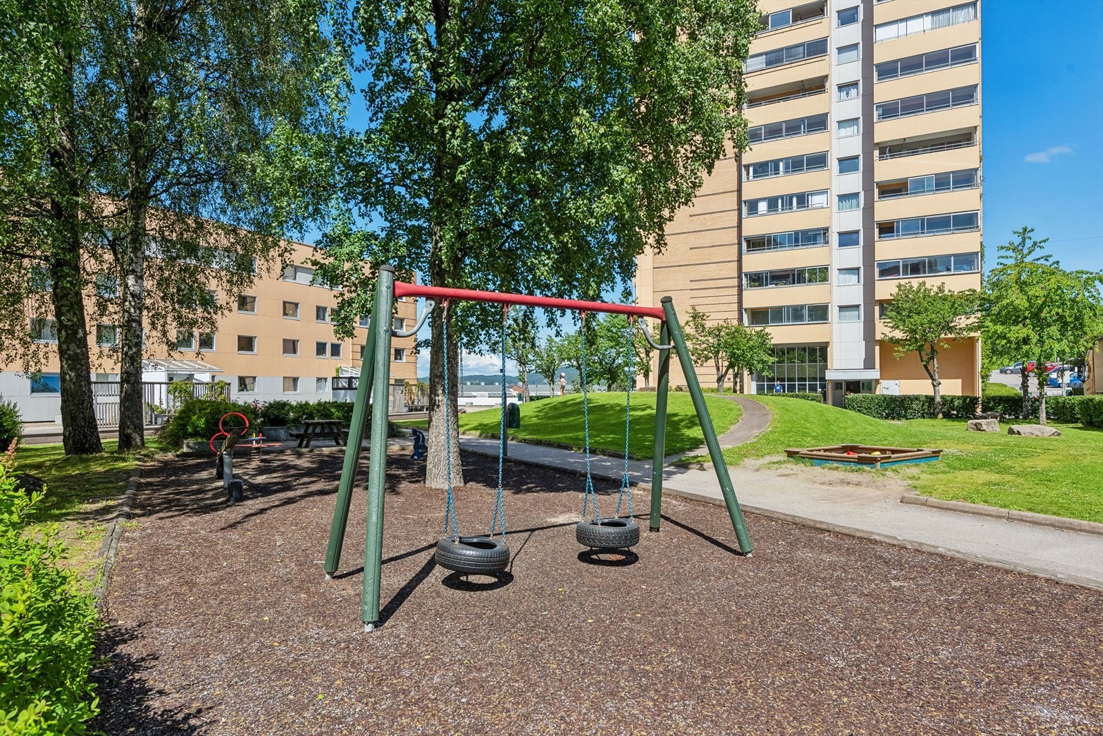 Fellesareal opparbeidet med asfalterte adkomstveier/plasser, gressplen, beplantning, trær, lekeapparater, parkeringsarealer m.m Galleribilde