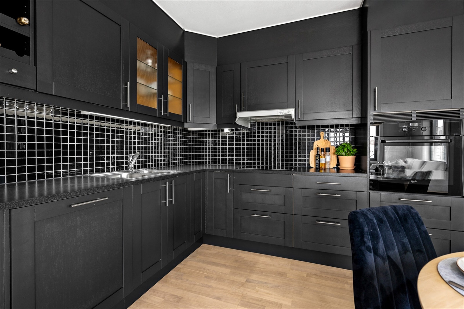 Innredningen består av mørke glatte skapfronter, benkeplate av laminat og oppvaskkum av rustfritt stål. Videre er det fliser på vegg mellom kjøkkenbenk og overskap, samt benkeskapsbelysning og stikkontakter over kjøkkenbenk. Galleribilde