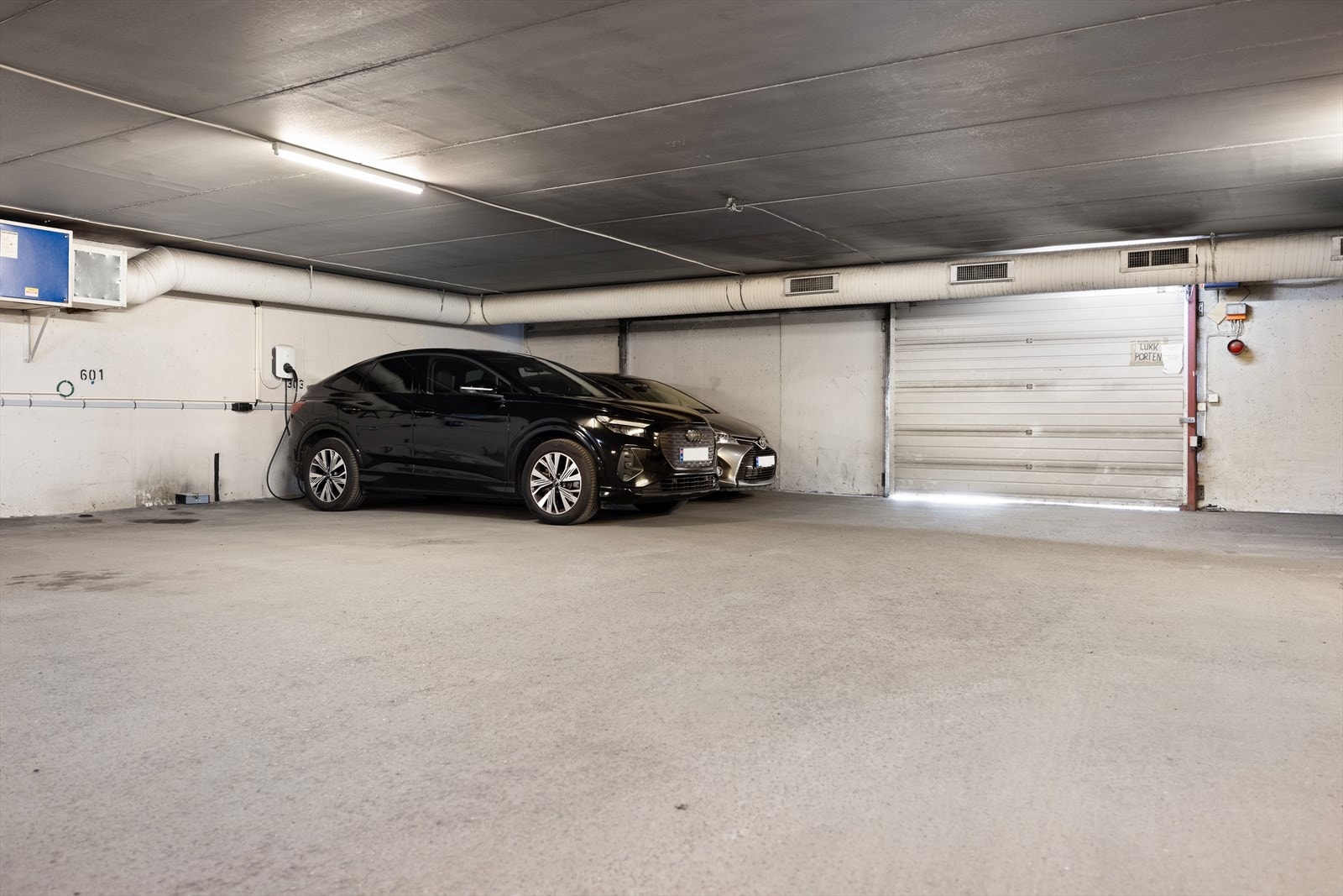 Egen parkeringsplass i garasjekjeller med lader til elbil (plassen med den sorte bilen). Galleribilde