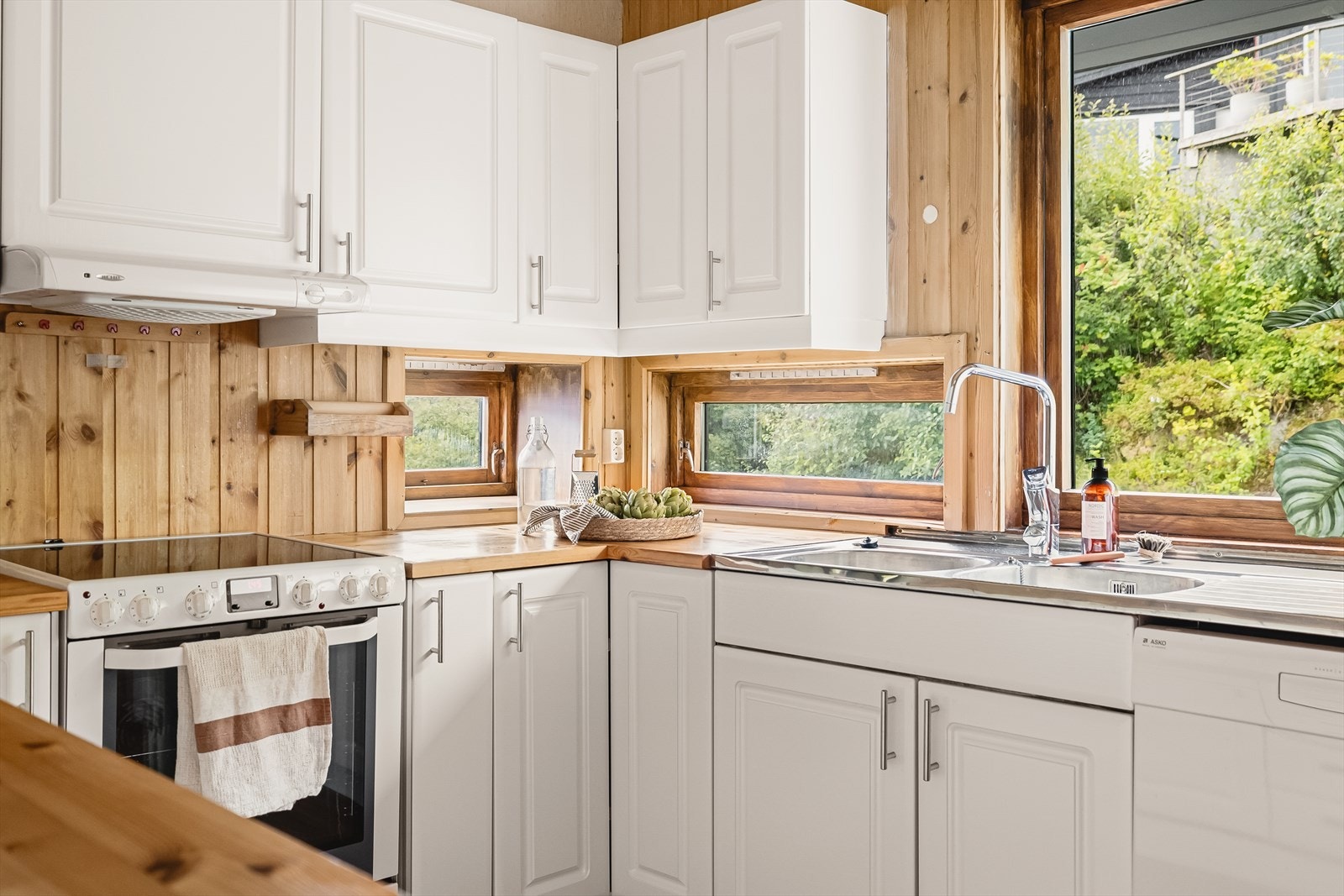 Kjøkkeninnredningen har profilerte hvite fronter (ny i 2017), heltre benkeplate i furu, stål vaskekum, opplegg for oppvaskmaskin og ventilator som fører ut gjennom yttervegg. Galleribilde