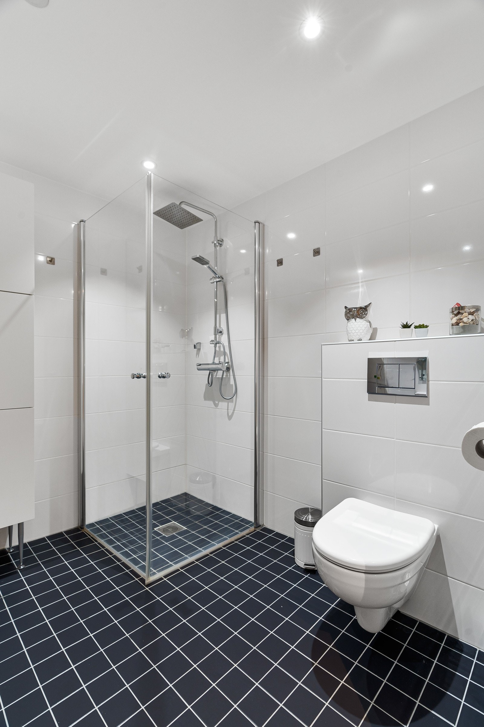 Flislagt moderne bad med stort dusjhjørne, praktisk vegghengt wc og opplegg for vask/tørk. Galleribilde