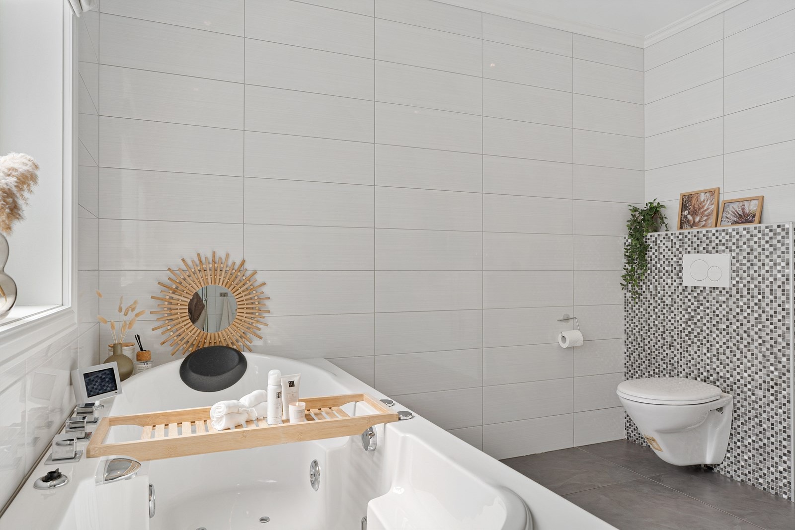 Badet er innredet med badekar, vegghengt toalett, dusjkabinett og pen baderomsinnredning Galleribilde