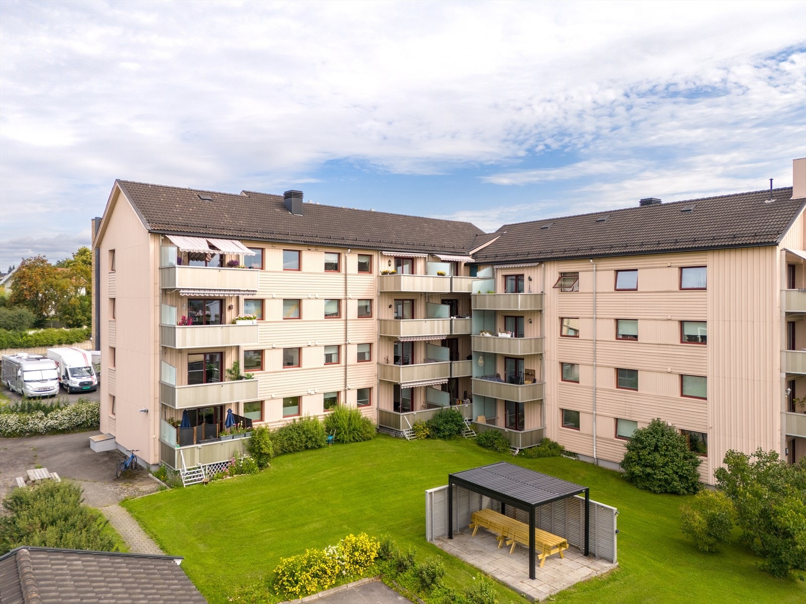 Felles tomt i borettslaget med asfalterte adkomstveger, felles biloppstillingsplasser, garasjeanlegg og park- og plenarealer med noe prydvekster. Galleribilde