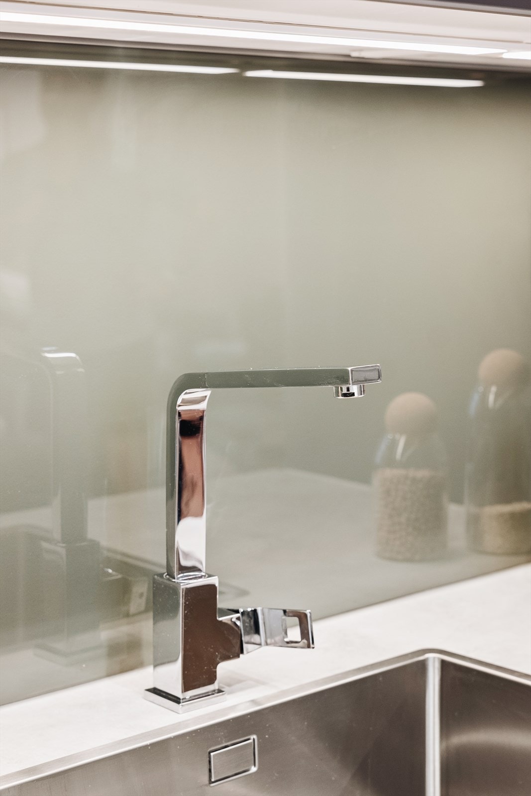 Stilren kjøkkenvask i stål og lys under overskap. Galleribilde