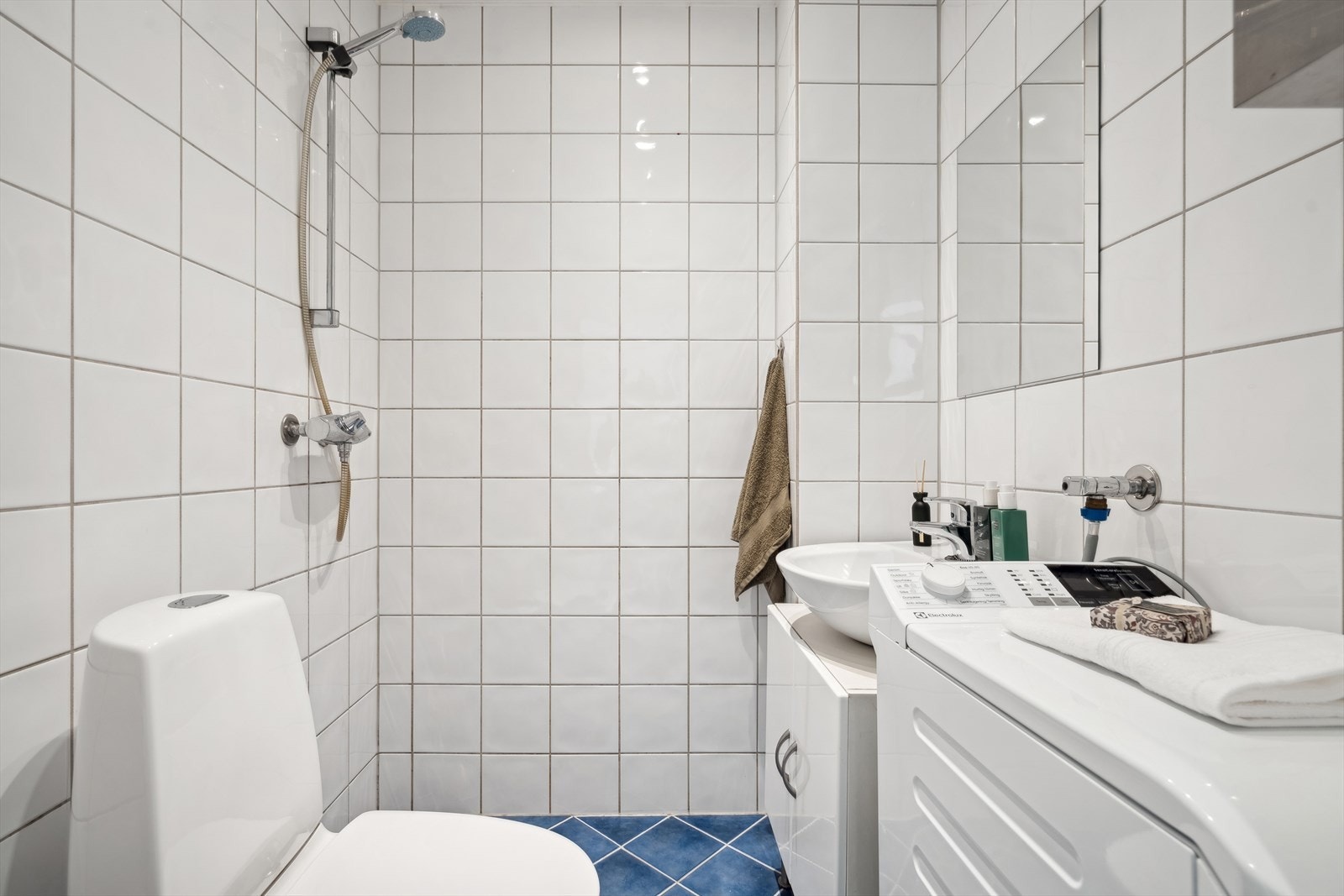 Flislagt baderom med fin innredning, servant, dusj og toalett. Opplegg for vaskemaskin. Galleribilde