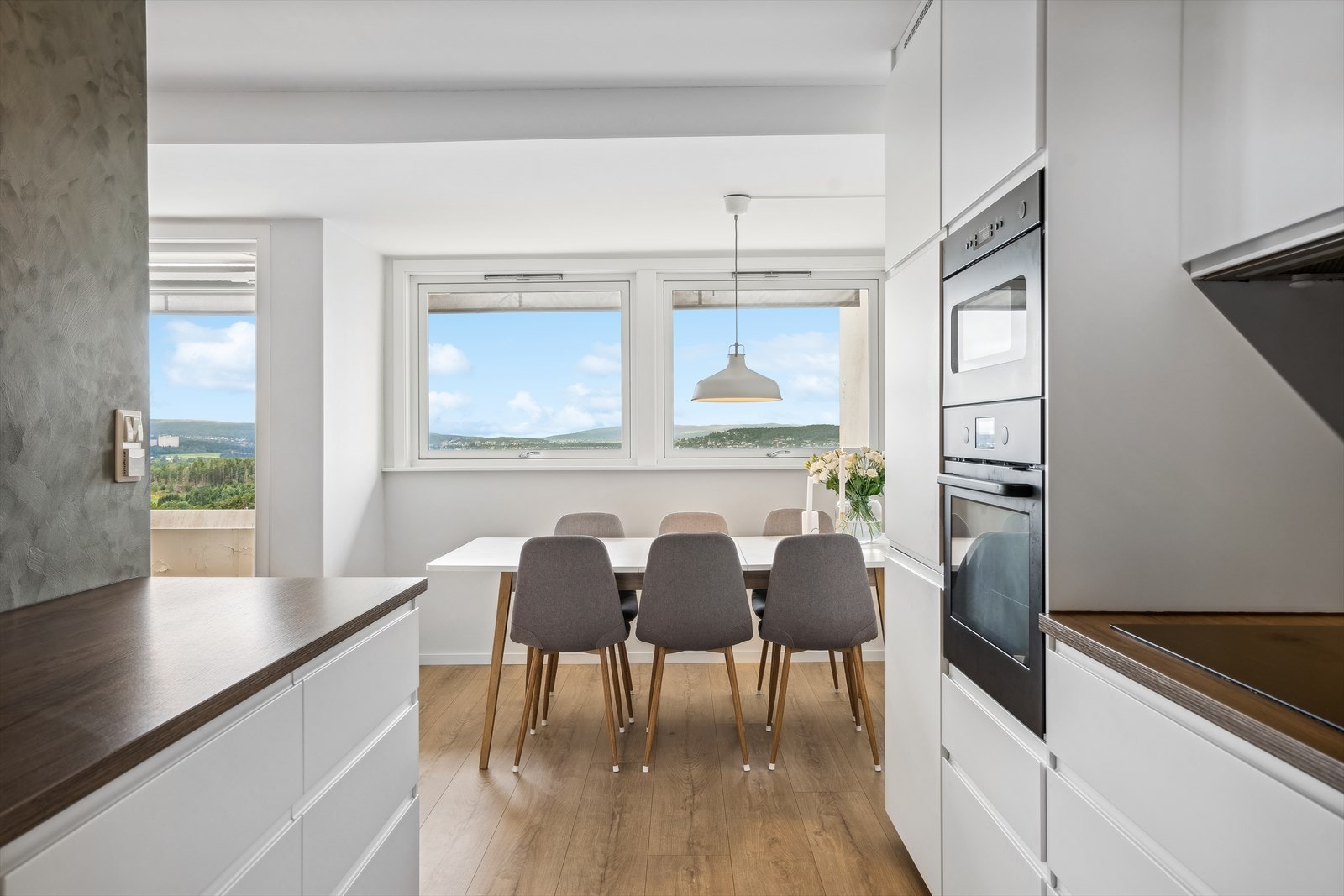 Benke- og overskap med slette fronter, benkeplate av laminat og plater på vegg over benk. Integrert platetopp, komfyr, mikro, kjøl/frys og oppvaskmaskin. Galleribilde