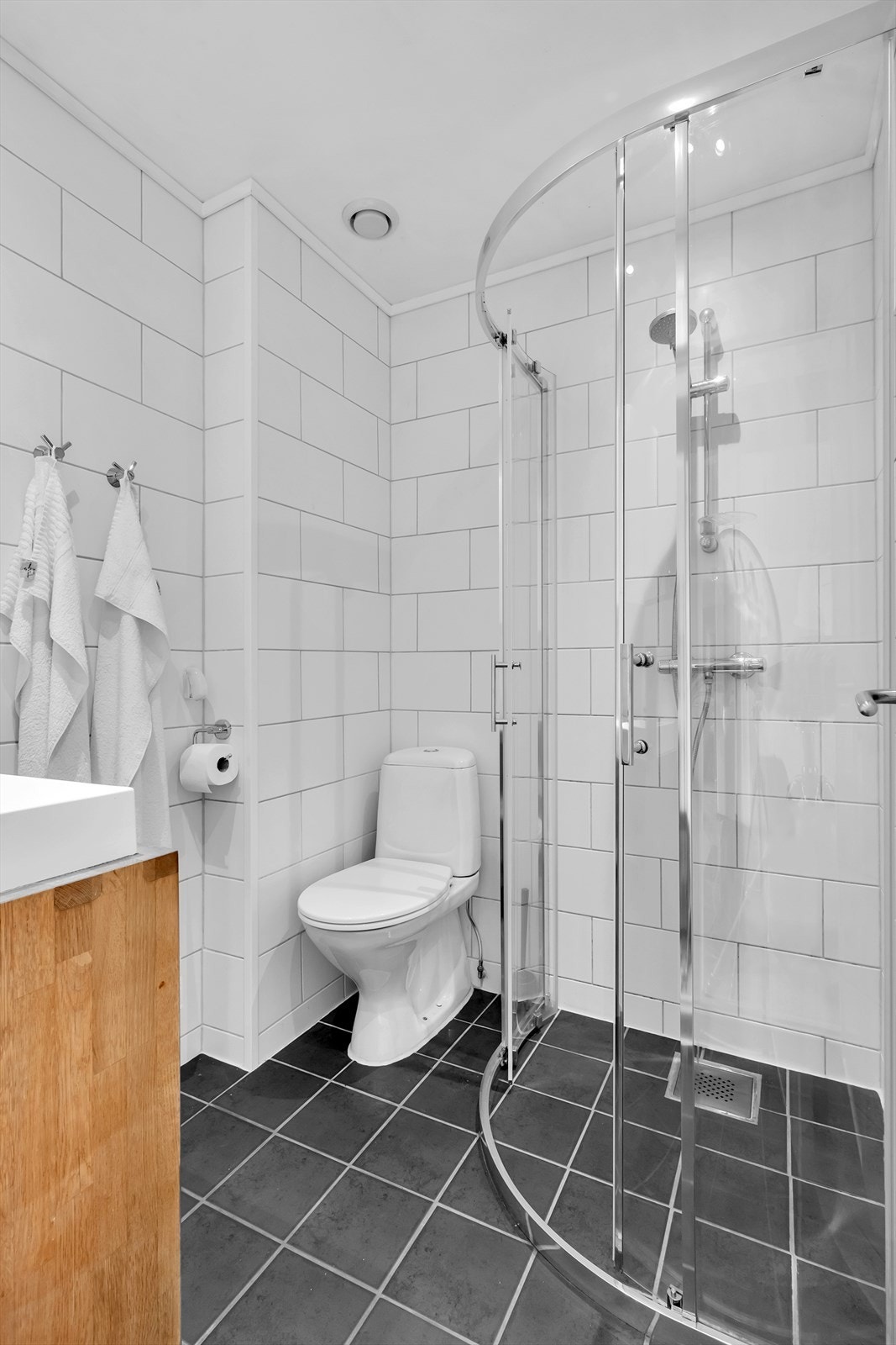 Badet er utstyrt med toalett, dusjdør/garnityr og servant med benk under Galleribilde