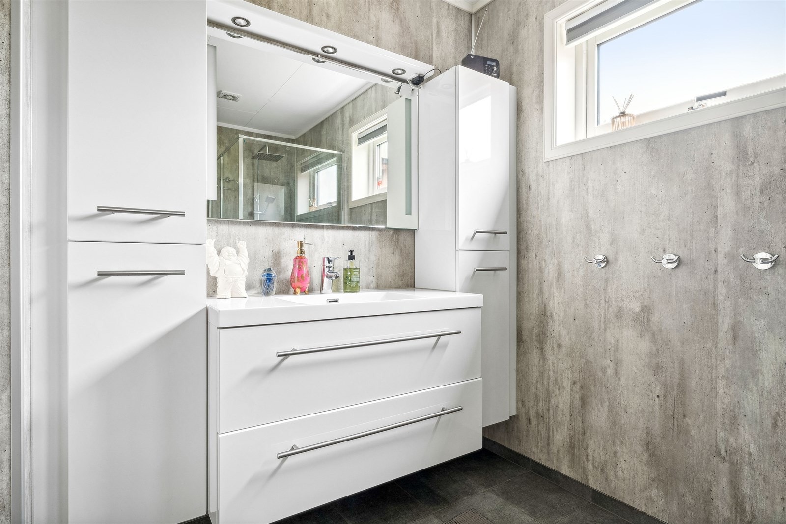 Badet har innredning med nedfelt servant, toalett og dusjvegger/hjørne, samt baderomsinnredning med laminerte fronter og skuffer. Galleribilde