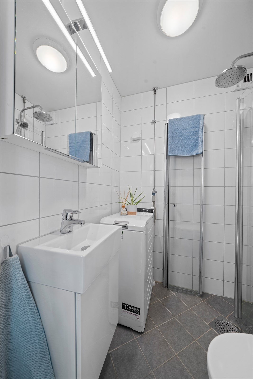 Innredning med vegghengt klosett, servantinnredning, servant med ettgreps blandebatteri, speilskap med belysning, dusjdører, dusjarmatur, opplegg og plass til vaskemaskin. Galleribilde