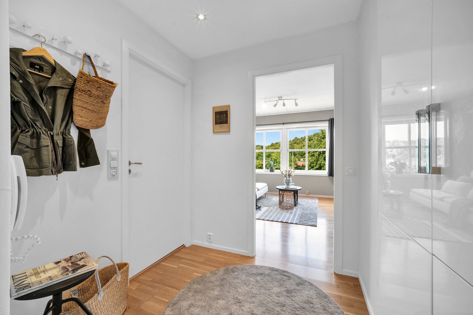 Romslig entré med direkte inngang til stue-området og bad. Entréen er malt i en tidløs hvit fargetone på vegg med spotter i tak. Galleribilde