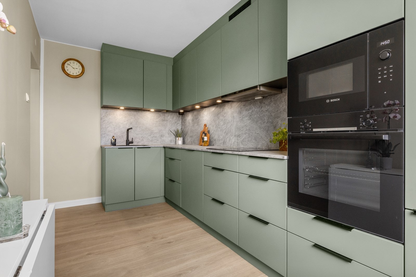 Kjøkkeninnredning med glatte fronter og laminat benkeplate med underlimt kum. Stekeovn, platetopp, Micro, kjøl/frys og oppvaskmaskin er integrert i innredningen. Galleribilde