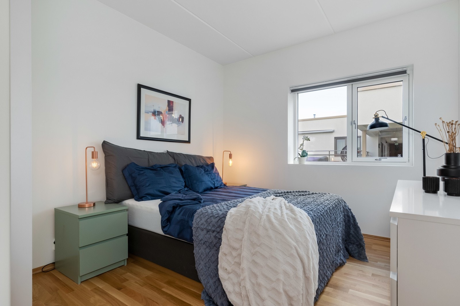 Leiligheten har to lyse soverom som er oppmålt til 11 og 8 kvm. Her er soverom 1 avbildet. Lyse vegger og eikeparkett på gulv. Galleribilde