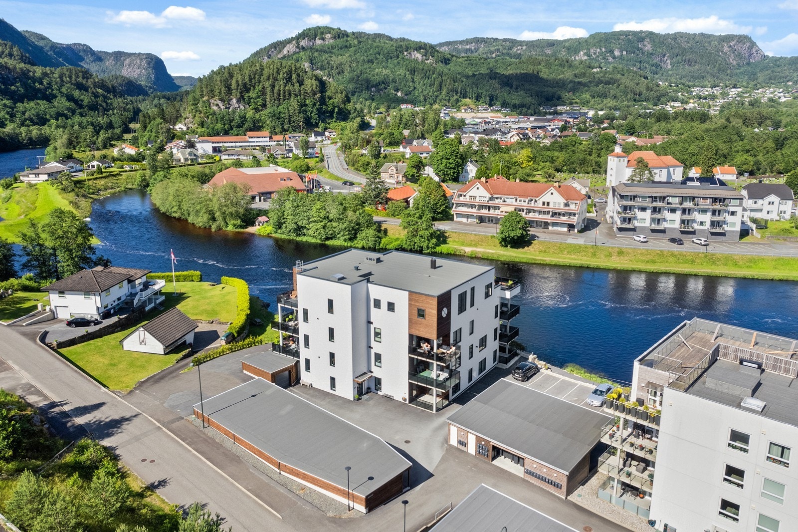 Tomten er flott opparbeidet med steinsatt mur med elvepromenade i front. Asfaltert stor gårdsplass med gode parkeringsmuligheter. Like ved er det også badestrand. Galleribilde
