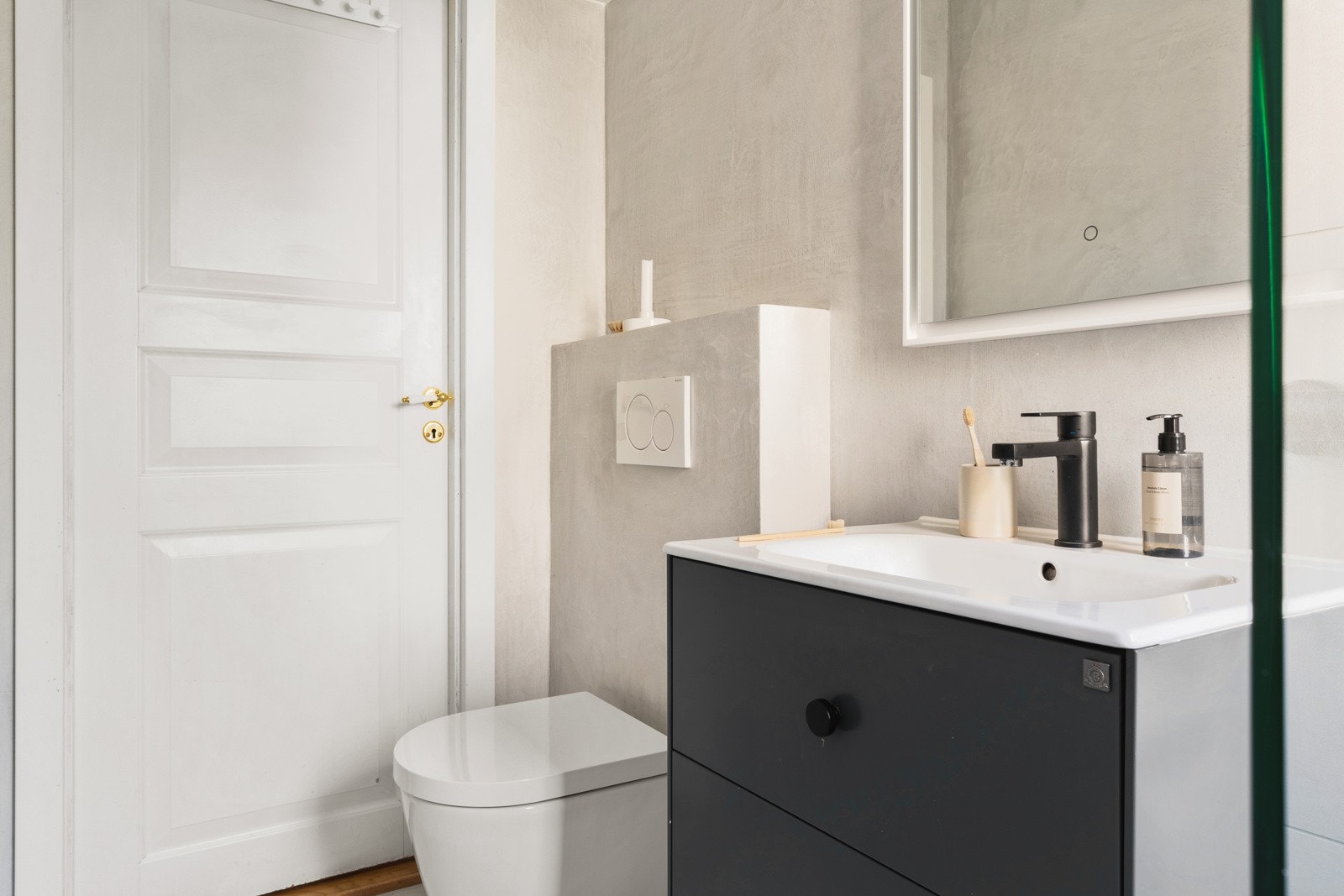 Rommet er innredet med dusj med glassvegg, vegghengt toalett og en praktisk baderomsinnredning. Galleribilde