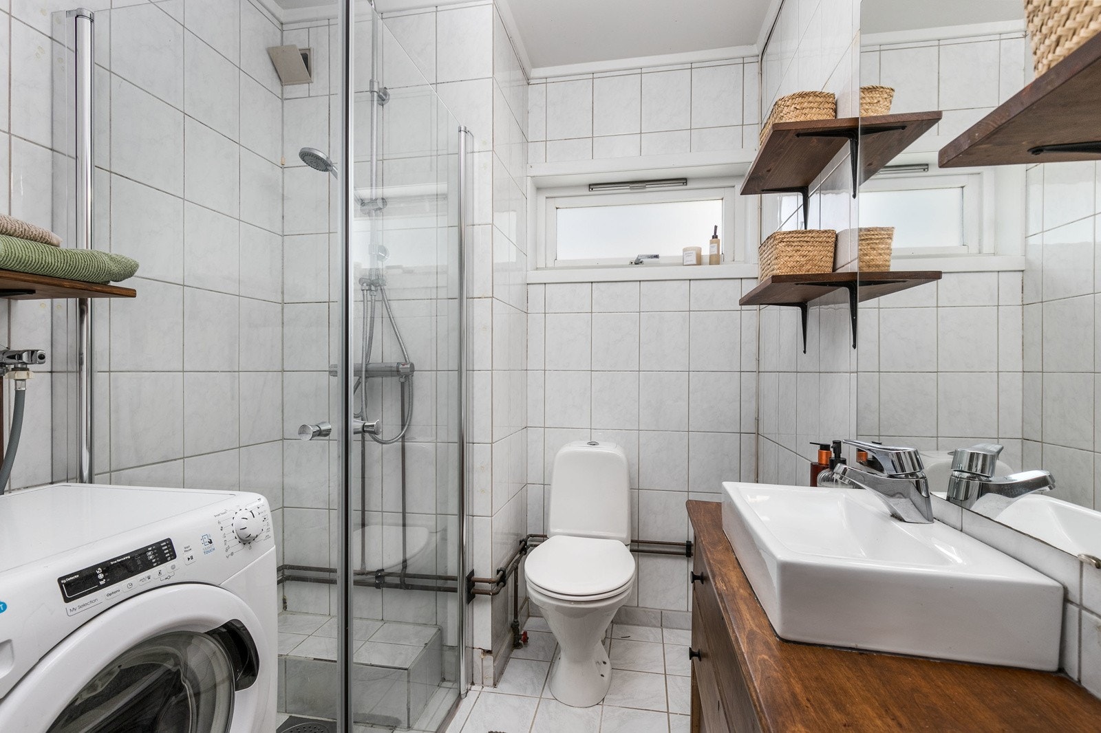 Eldre flislagt bad med behov for oppgradering. Innredningen består av servantmøblement med underskap, speil, toalett, samt separat dusjhjørne. Galleribilde