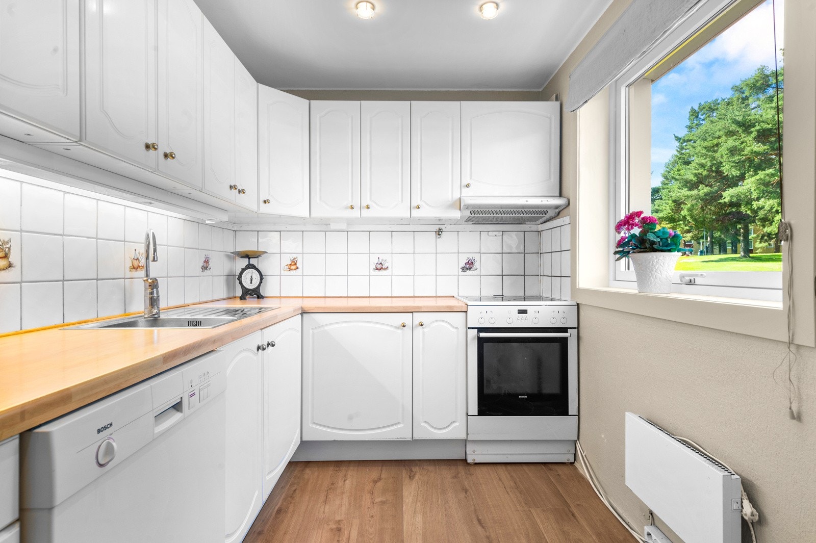 Kjøkkenet ligger praktisk til i et eget rom med vindu mot nordvest, og har adkomst via skyvedør fra spisestuen og gangen. Galleribilde