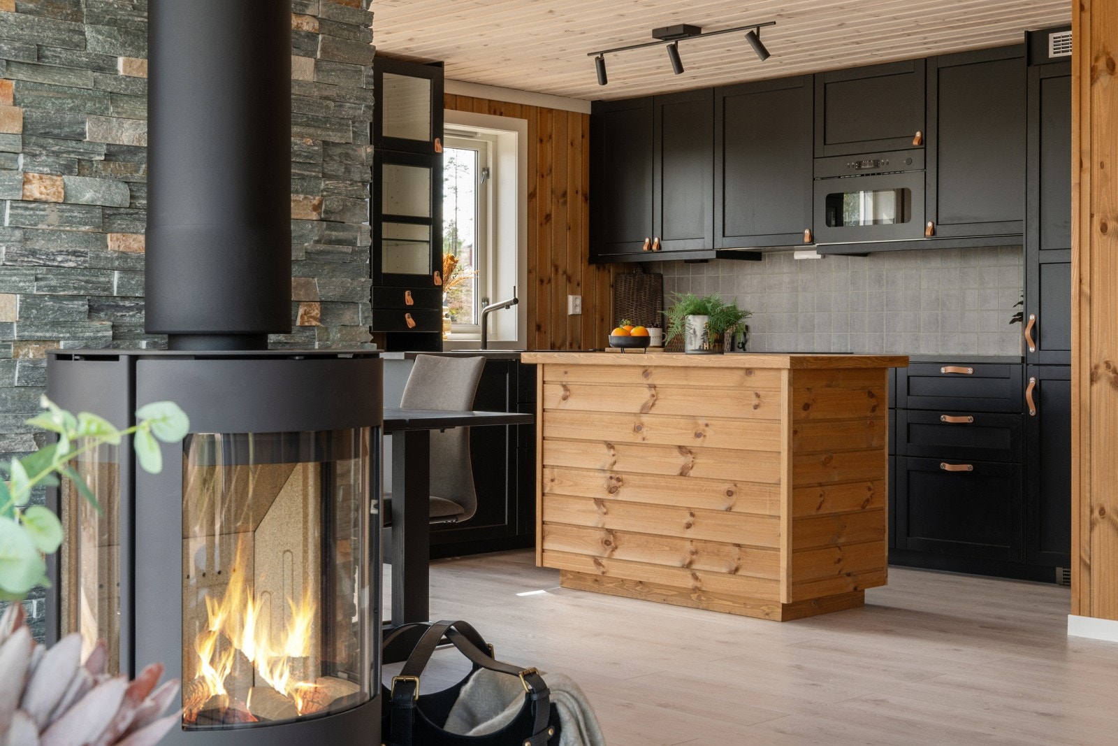 Åpen stue- og kjøkkenløsning, med peisovn og komplett kjøkken. Galleribilde