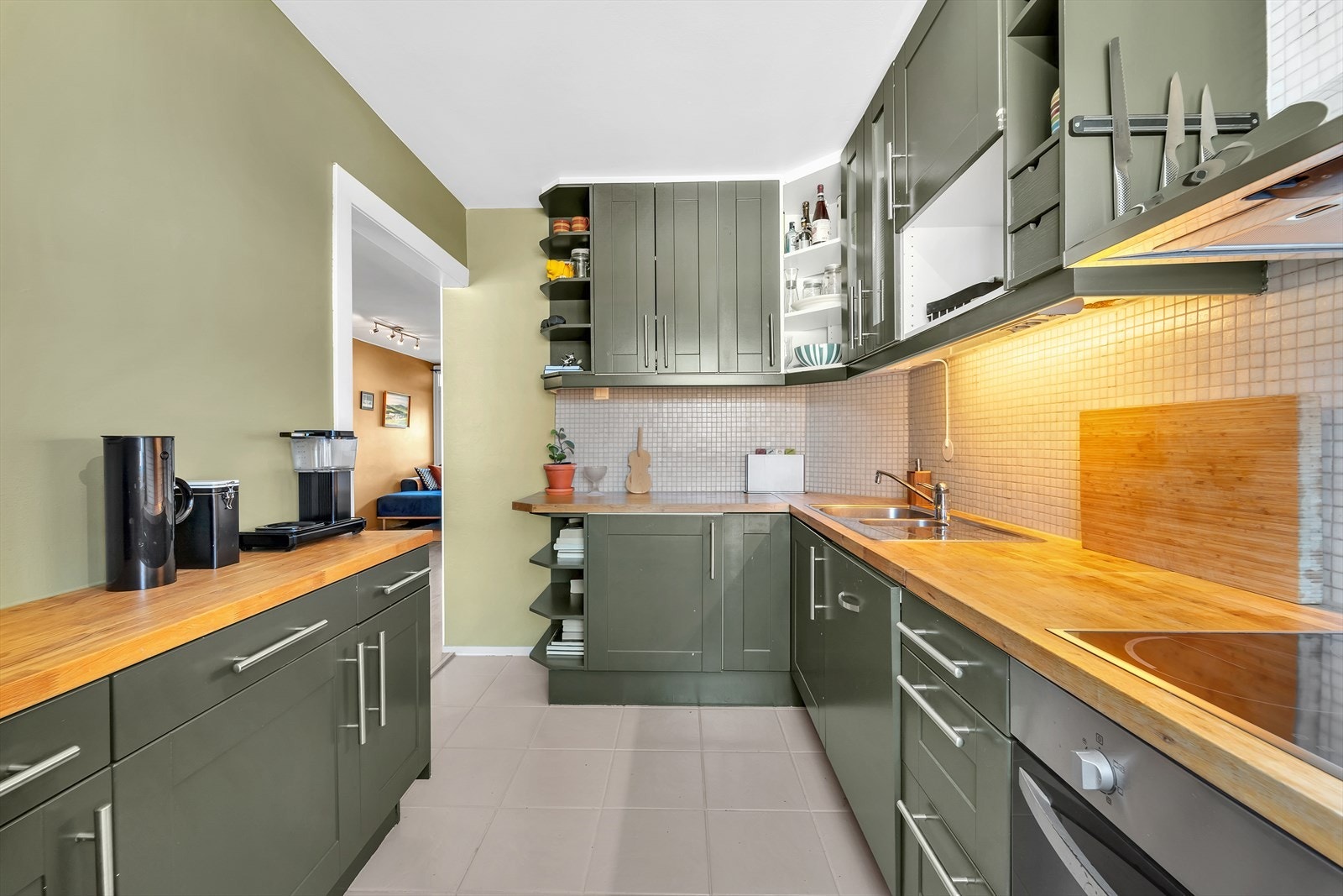 Benkeplate i tre og dobbel oppvaskkum i stål, med ett-greps blandebatteri. Integrert komfyr, oppvaskmaskin, frittstående kjøleskap og frys. Galleribilde