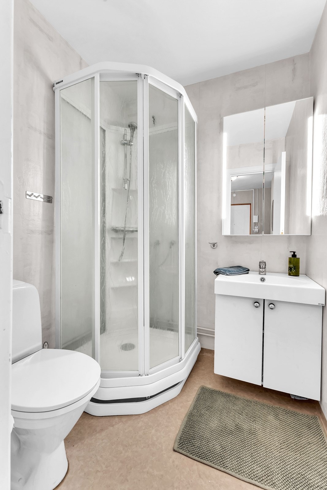Badet er innredet med servant på hvit skapinnredning, dusjkabinett, toalett. Galleribilde