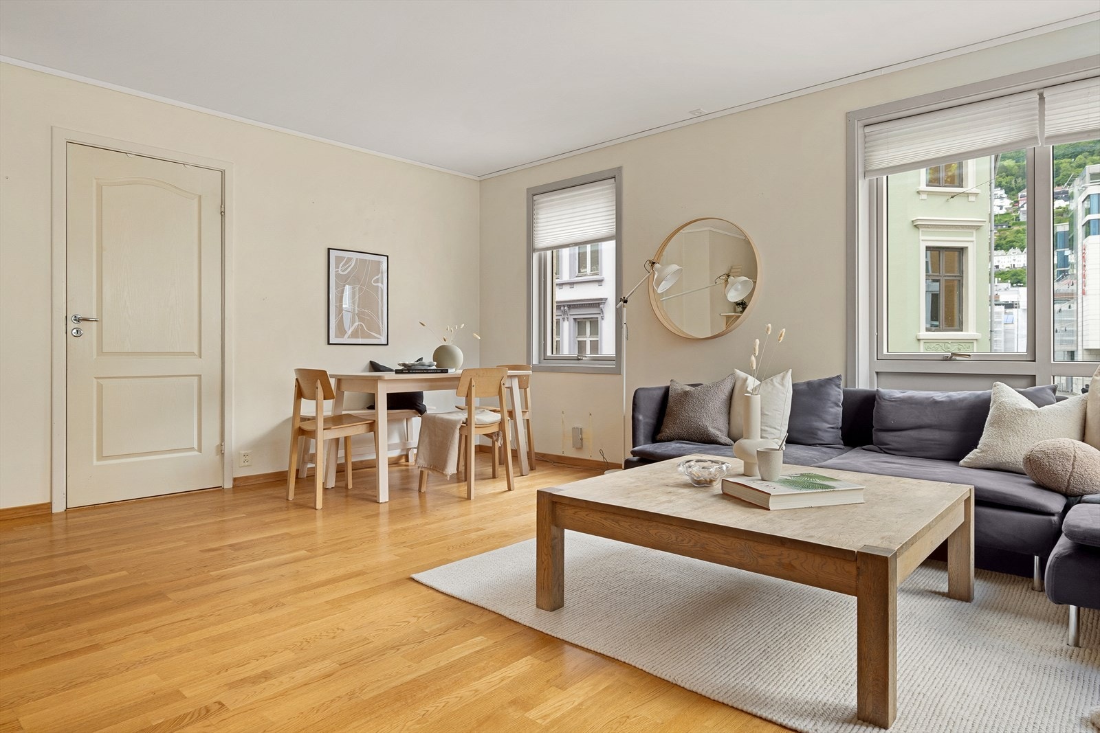 Plass til både sofagruppe og spisebord i stuen. Parkett på gulv og veggflater malt i duse, moderne fargetoner. Galleribilde