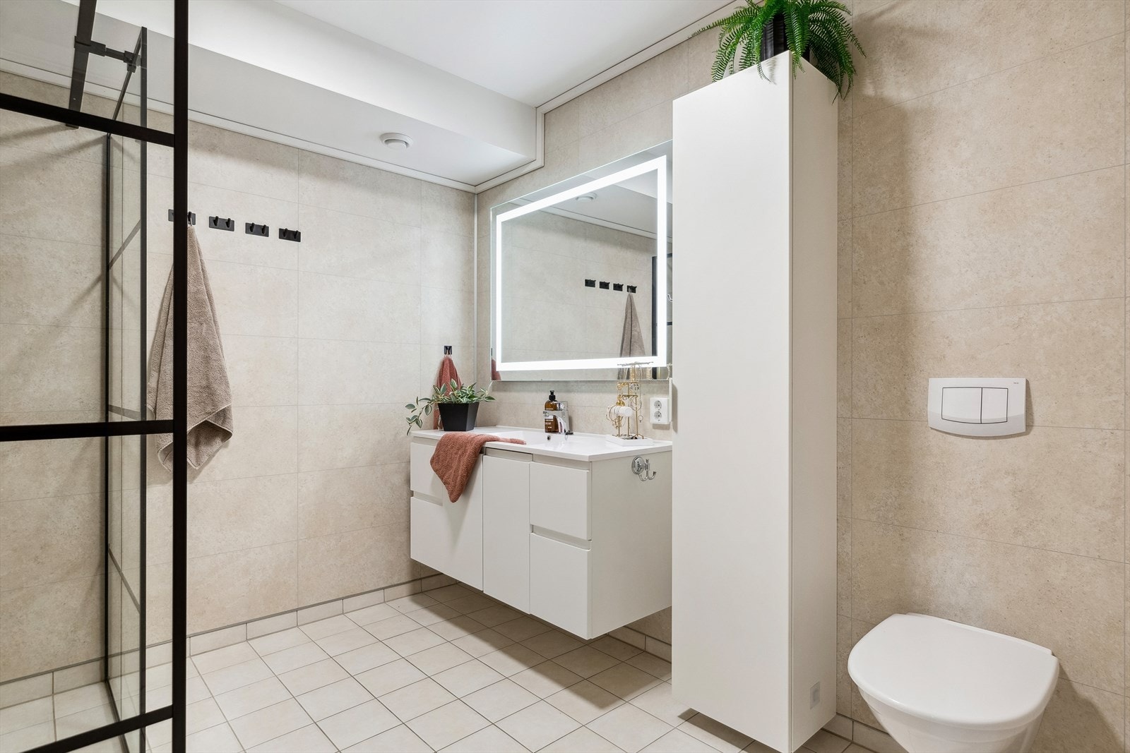 Badet i sokkeletasjen har flislagt gulv, våtromsplater på vegger, veggmontert toalett og dusjnisje. Galleribilde