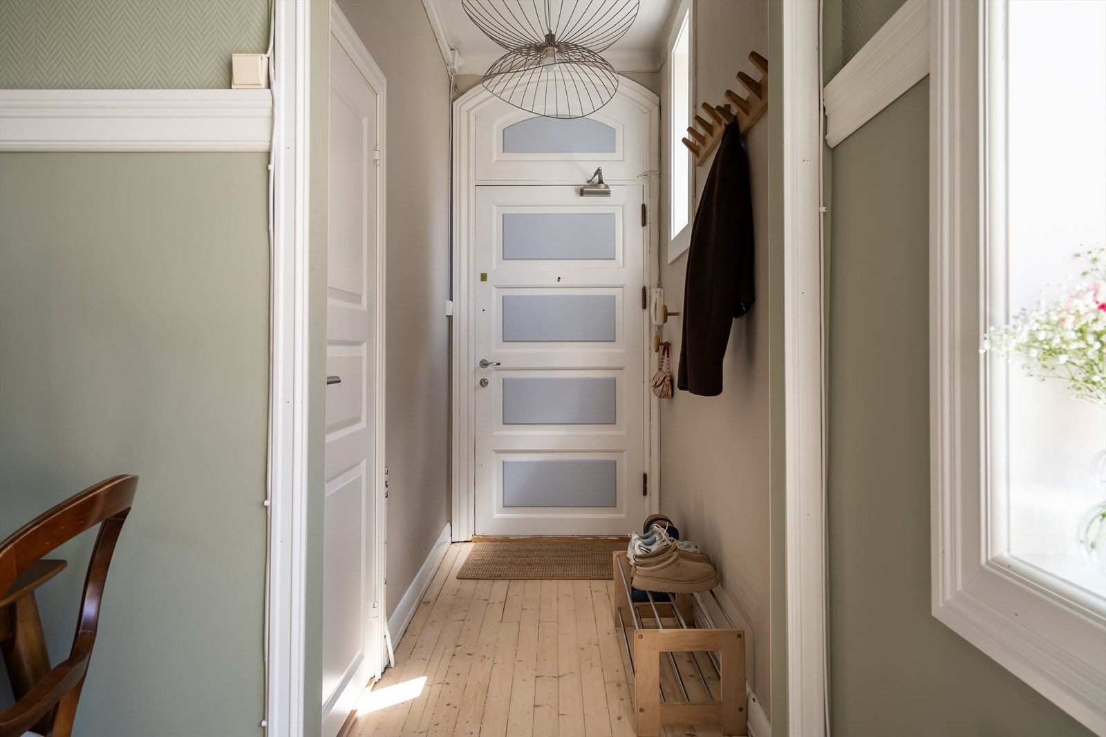En lys og innbydende entré med plass til å henge fra seg yttertøy og sette fra seg sko. Originale detaljer. Galleribilde